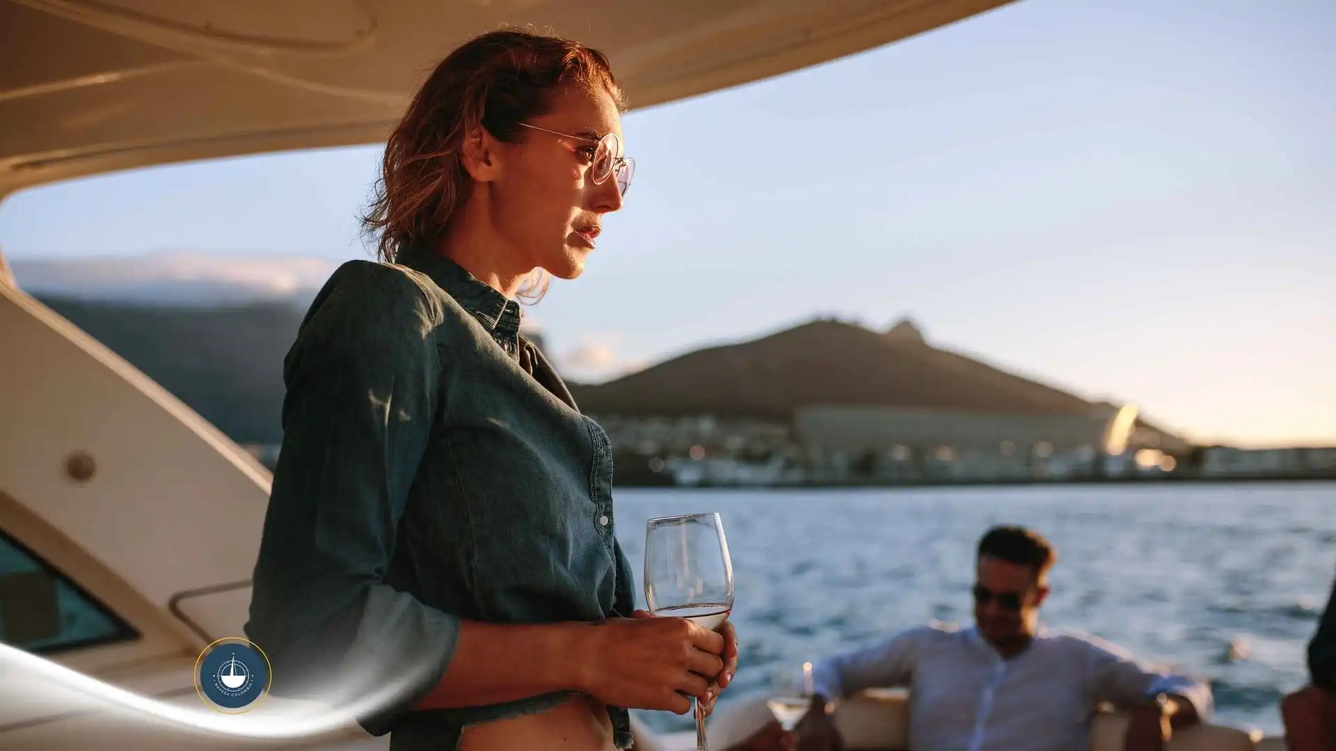 mujer a bordo de un yate con una copa en la mano y otras personas de fondo Fiestas privadas en yate en Cartagena: organiza tu evento en el agua navega colombia