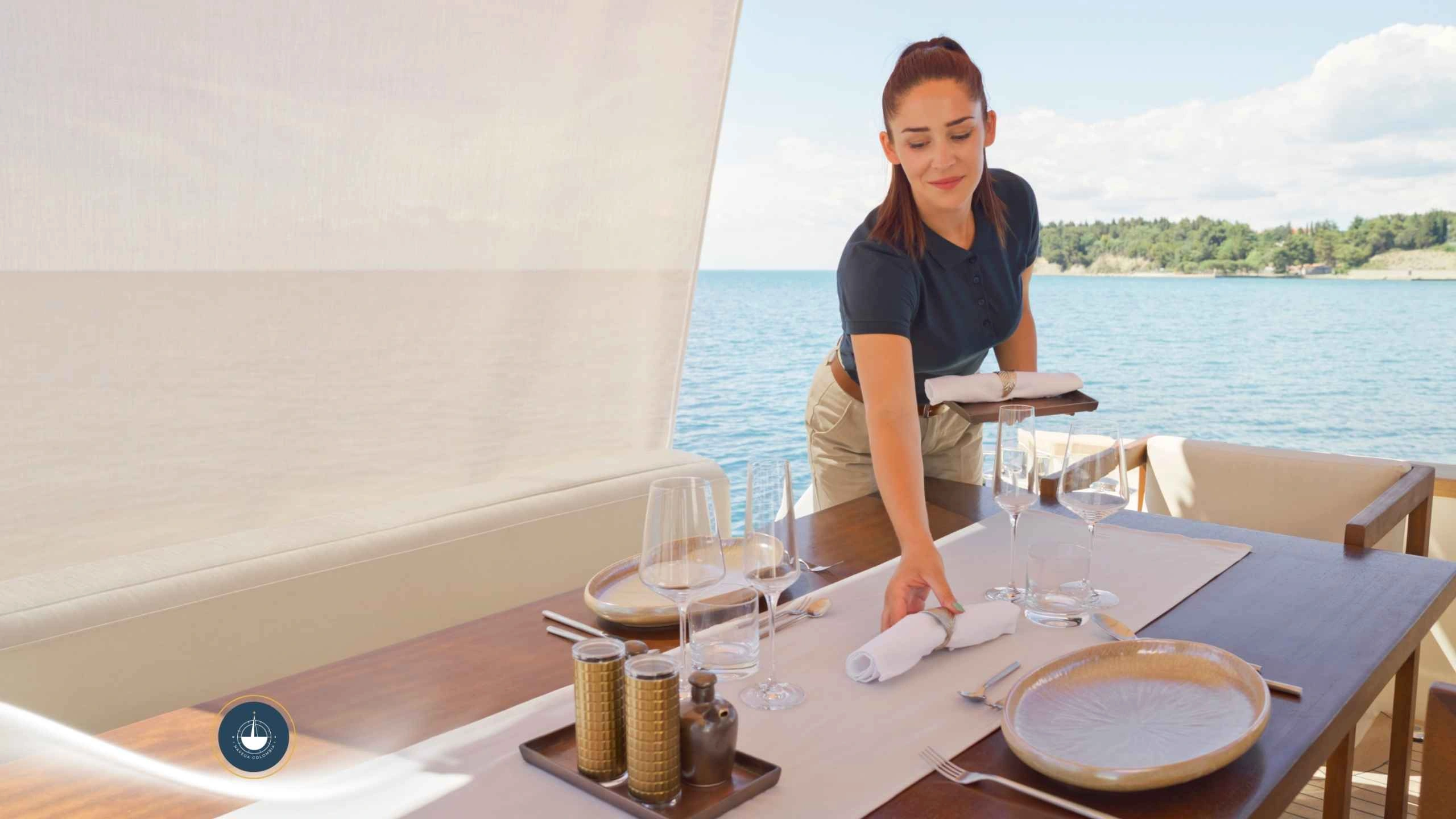 persona que sirve una mesa a bordo de un yate con el fondo del mar Cómo cotizar el alquiler de un yate en Cartagena: guía paso a paso navega colombia