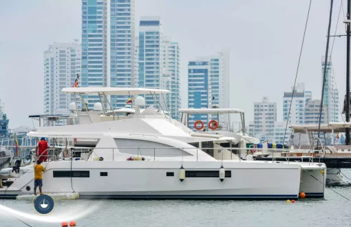 yate en el puerto de cartagena dos personas lo están alistando y se ven los edificios de fondo Capacidad de yates en Cartagena Navega Colombia